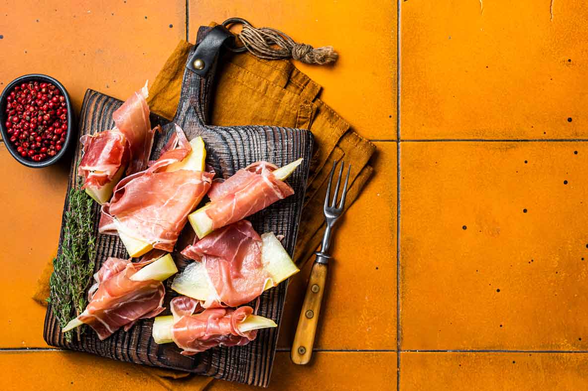 Melón con jamón sobre tabla de madera